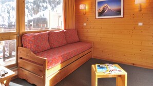 A wooden cabin room with a sofa, a small table, and a picture on the wall. - Comfortable divisible studio 4 pers, near slopes and shops (Plagne Bellecôte)