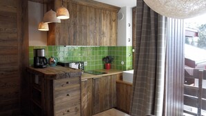 A rustic kitchen with wooden cabinets, a green tiled backsplash, and a built-in stove. - Apartment at Base of Slopes • 5 pers • Slope View (Belle Plagne)