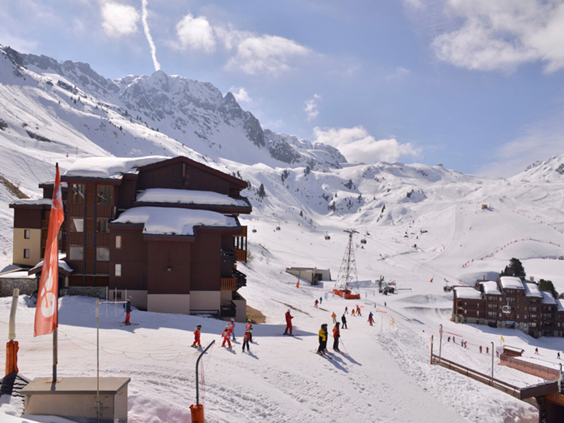 A ski resort with a large wooden building, ski slopes, and a mountain backdrop.