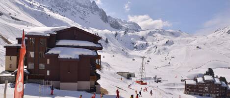 A ski resort with a large wooden building, ski slopes, and a mountain backdrop.