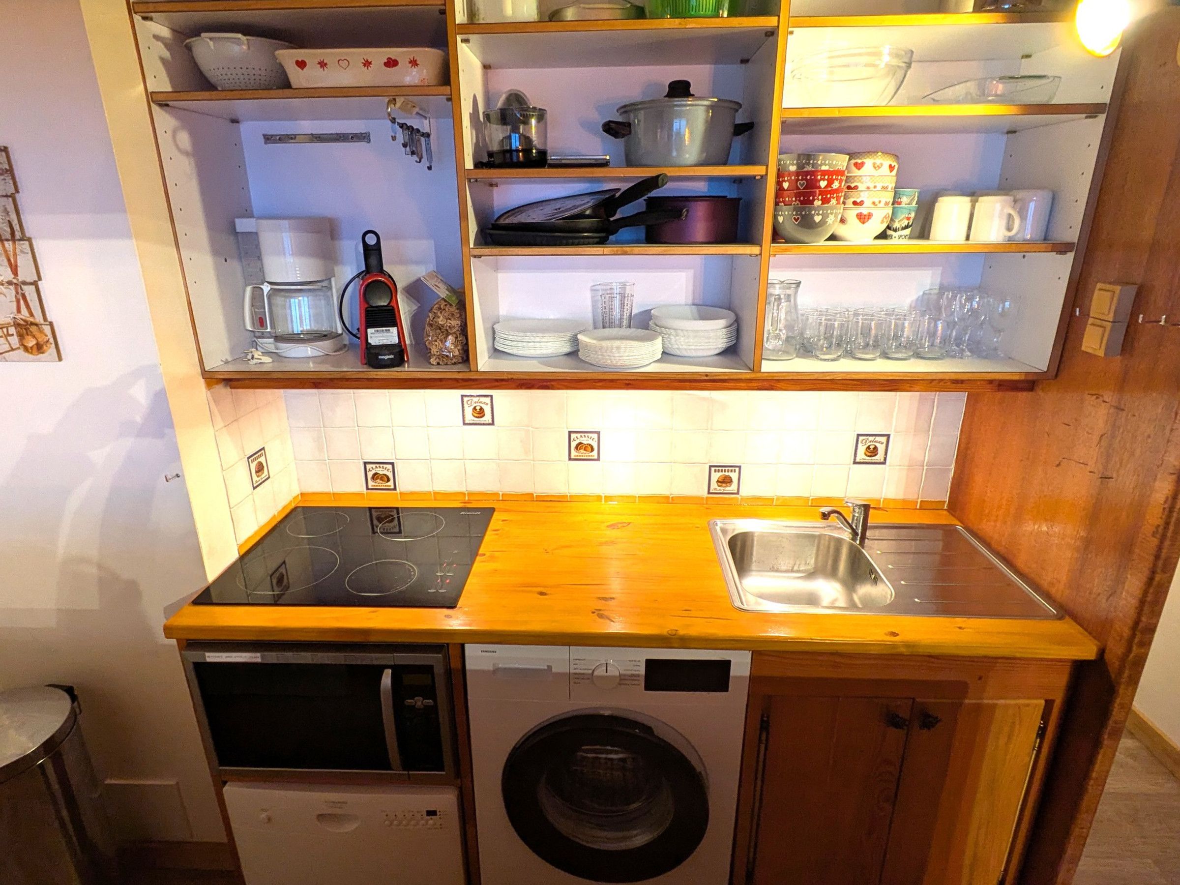 A compact kitchen with a built-in oven, microwave, and washing machine.