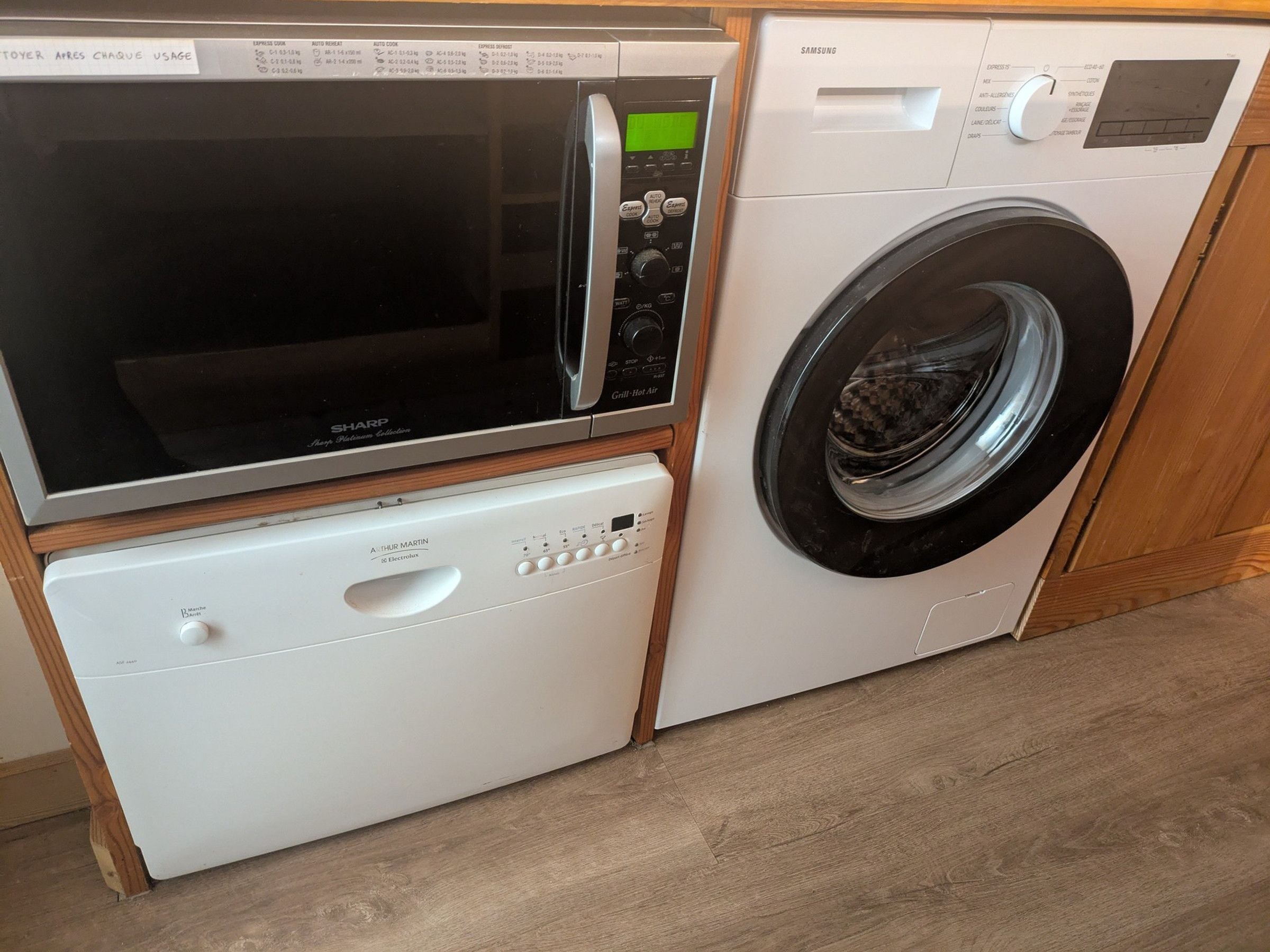 Un espace buanderie compact comprenant un four à micro-ondes, un lave-linge et un lave-vaisselle.