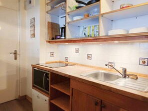 A kitchen with wooden cabinets, a stainless steel sink, and a dishwasher.