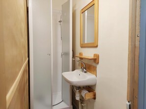 A bathroom with a white sink, wooden towel holder, and a mirror.