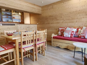 Ein Holzinterieur mit einem Esstisch, Stühlen, einer Couch und einem Bett.