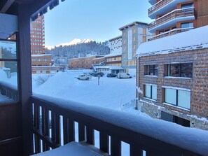 Una zona residencial cubierta de nieve, con edificios de varios pisos, cielo despejado y una vista de una cadena montañosa al fondo.