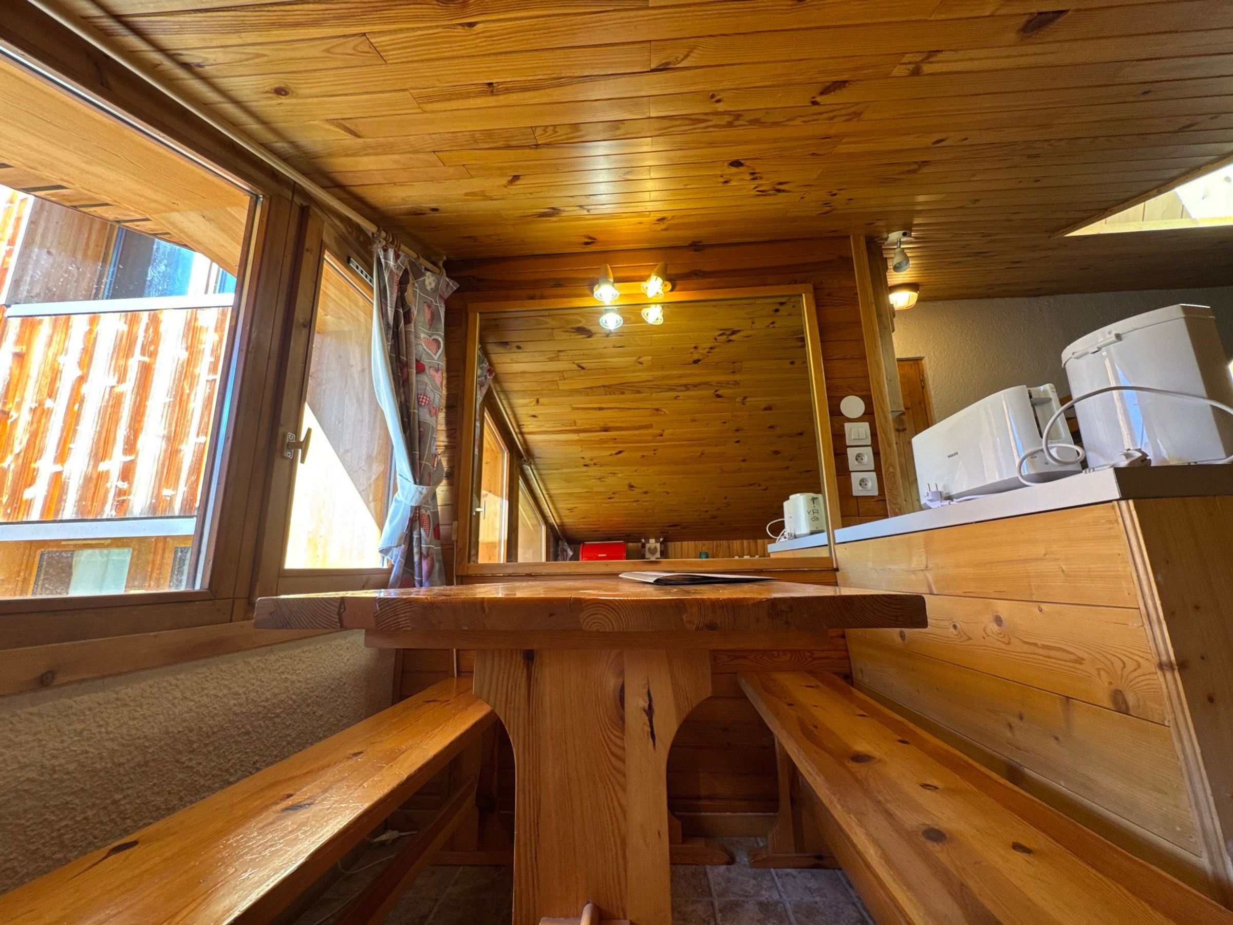 A wooden interior with a bench, a table, and a window.