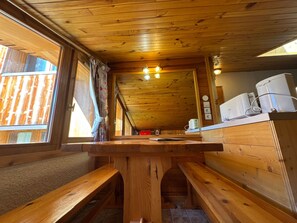 A wooden interior with a bench, a table, and a window.