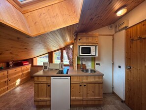 A compact kitchen with wooden cabinetry, a built-in microwave, a sink, and a dishwasher.