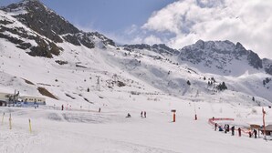 A snowy mountain landscape with ski slopes, a ski lift, and a few skiers.