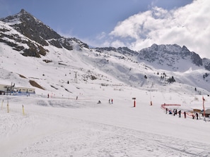 A snowy mountain landscape with ski slopes, a ski lift, and a few skiers. - Cozy ski-in studio, pets allowed (Belle Plagne)