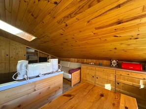 A wooden interior with a kitchenette, a sofa, and a dining table.
