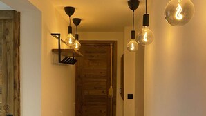 A hallway with wooden paneling, a wooden door, and pendant lighting fixtures.