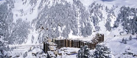 A snow-covered mountain with a ski resort and buildings in the foreground.