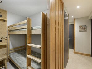 A bunk bed room with a wooden door and a small shelf.