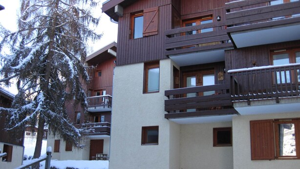 A multi-story building with wooden balconies and windows, surrounded by snow-covered ground and trees. - Spacious studio near slopes and center, pets allowed (La Plagne Montchavin Les Coches)