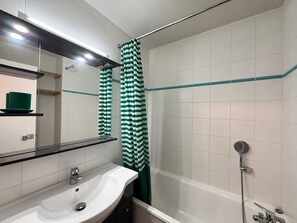 A modern bathroom with a white sink, a mirror, and a shower area.