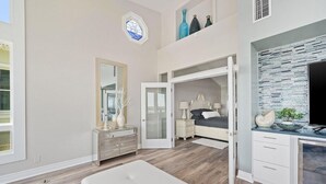 A bedroom with a bed, a dresser, a mirror, and a TV. - Beachfront Bliss: Spacious Deck, Grill & Unmatched Gulf Views! (Panama City Beach)