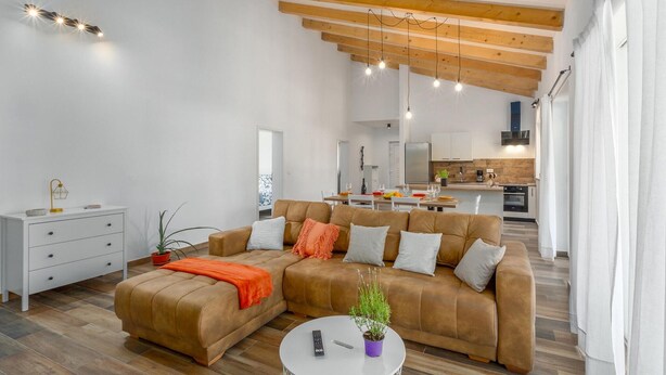A modern living room with a sofa, a coffee table, and a dining area in the background. - Pet friendly home in Debeljuhi (Debeljuhi)