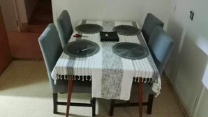 Una mesa de comedor con cuatro sillas, un mantel individual y un sujetamantas.