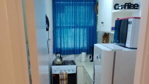 Una cocina compacta equipada con estufa a gas, microondas y refrigerador.