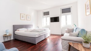 A modern bedroom with a grey sofa, a wooden coffee table, and a bed with a grey headboard. - Comfortable Apartments Vienna 1100  (Vienna)