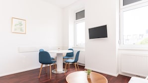 A modern room with a round wooden table, a white round table, and blue chairs. - Comfortable Apartments Vienna 1100  (Vienna)