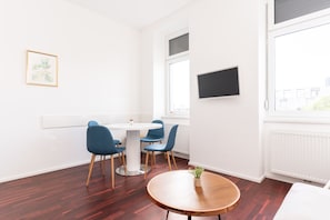 A modern room with a round wooden table, a white round table, and blue chairs.