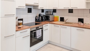 A modern kitchen with white cabinets, a wooden countertop, a built-in oven, a microwave, and a coffee maker. - Comfortable Apartments Vienna 1100  (Vienna)