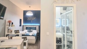A modern bedroom with a bed, bedside table, and a wall-mounted tree decoration.