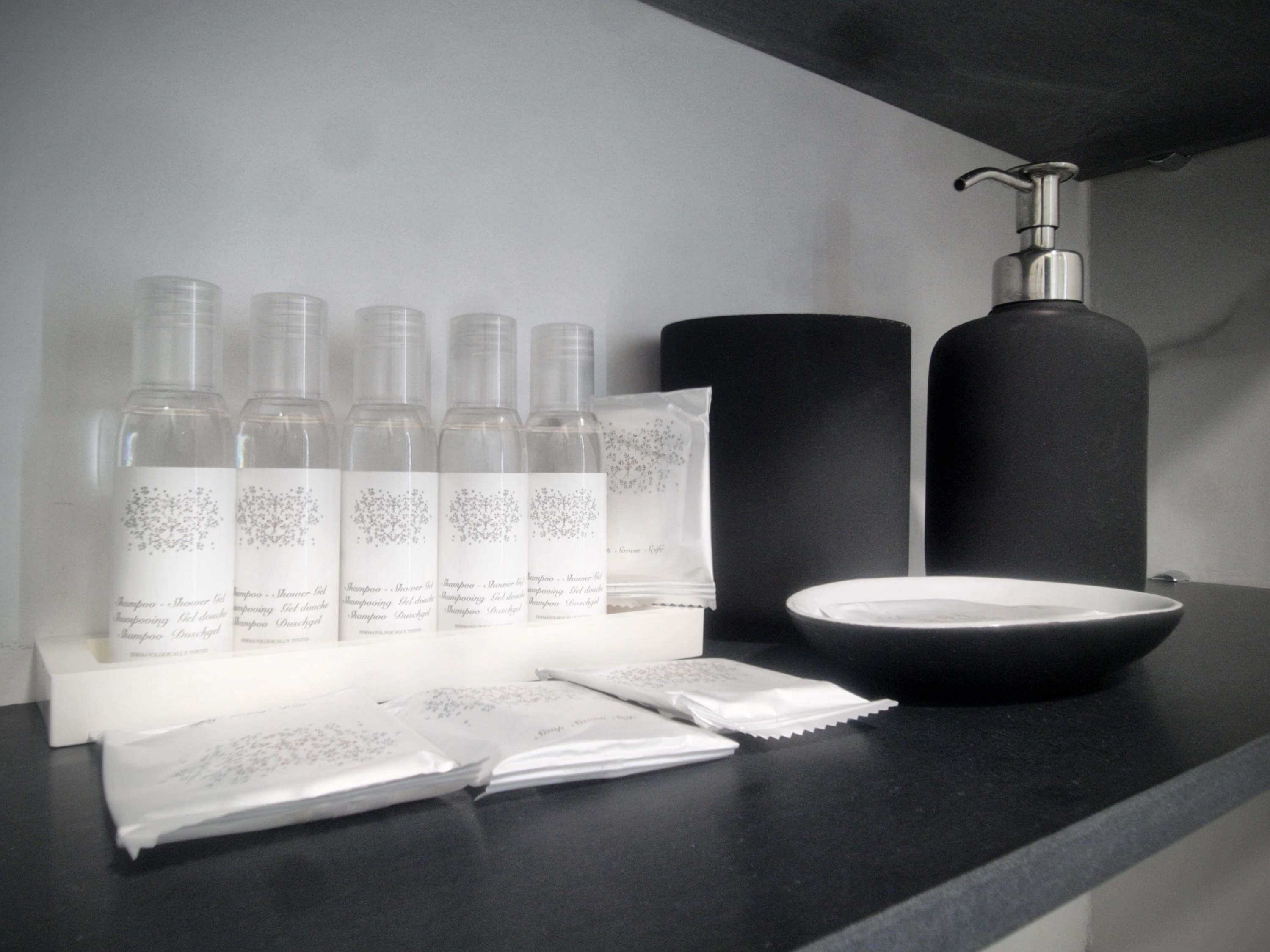 A bathroom counter with toiletries including bottles, a soap dispenser, and a bowl.