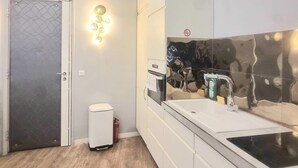 A modern kitchen with a white countertop, stainless steel appliances, and a decorative wall with a reflective pattern.