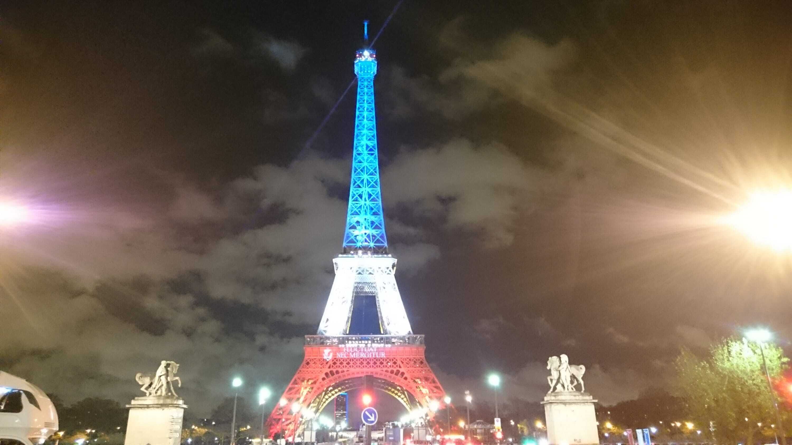 De Eiffeltoren 's nachts, verlicht met straatverlichting en beelden eromheen.