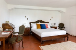 A bedroom with a wooden bed, a desk, a chair, and a nightstand.