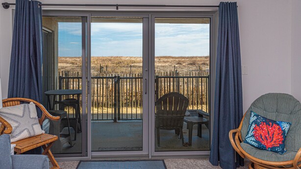 Une pièce dotée d’une porte-fenêtre coulissante donnant sur une terrasse aménagée avec une chaise, une petite table et un banc.