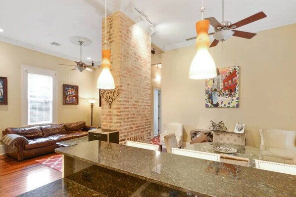 A spacious living area with a large brick fireplace, a dining table, and a sofa.