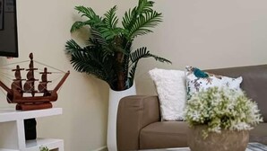 A living room with a white coffee table, a decorative ship model, a potted plant, and a book titled 'DECOR'. - Lux Suites Neema court Apartments (Nairobi)