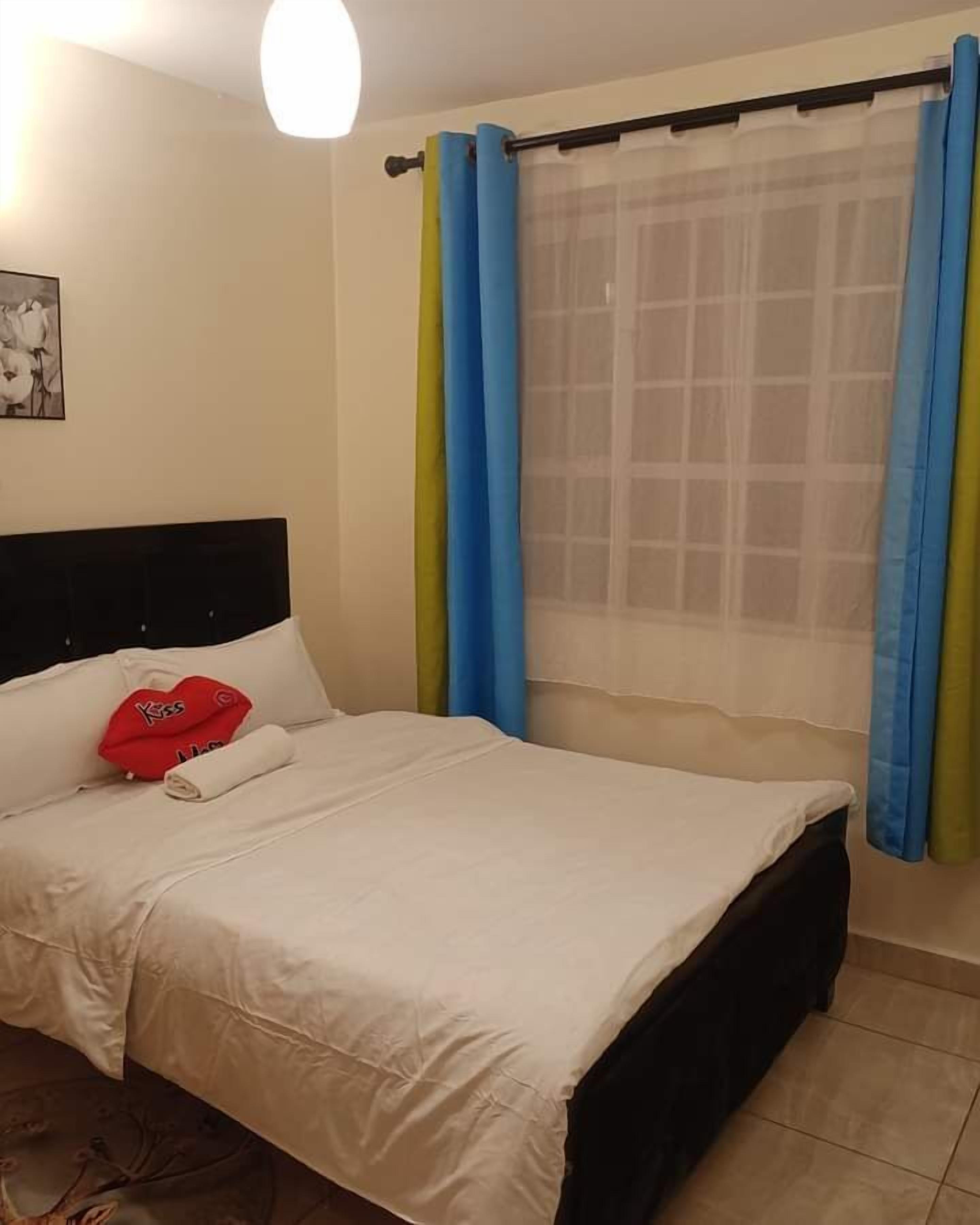 Un lit bien fait, avec une couette blanche et un oreiller rouge.