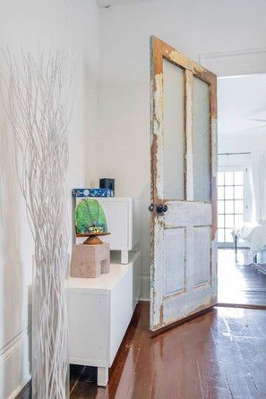 A room with a wooden door, a white dresser, and a decorative plant. - Irish Channel Apt w/ Balcony | Walk to Magazine St (New Orleans)