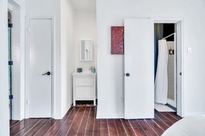 A hallway with a wooden floor, white walls, and a white door on the left. - Irish Channel Apt w/ Balcony | Walk to Magazine St (New Orleans)