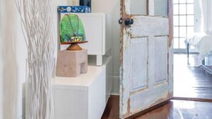 A room with a wooden door, a white dresser, and a decorative plant. - Irish Channel Apt w/ Balcony | Walk to Magazine St (New Orleans)