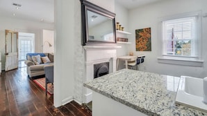 A modern kitchen with a granite countertop, white cabinetry, and a large mirror above the stove. - Irish Channel Apt w/ Balcony | Walk to Magazine St (New Orleans)