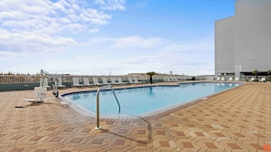 Una piscina con sillas de descanso y un edificio moderno al fondo.