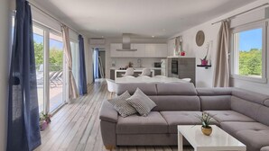 A modern living room with a grey sofa, a white coffee table, and a kitchen in the background. - Amazing home in Pazin (Pazin)