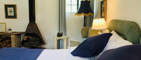 Une chambre d’hôtel avec un lit, une cheminée, une lampe et une petite table sur laquelle est posée une figurine de canard.