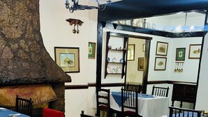 A restaurant with a rustic interior, featuring a thatched roof structure, wooden tables, and chairs.