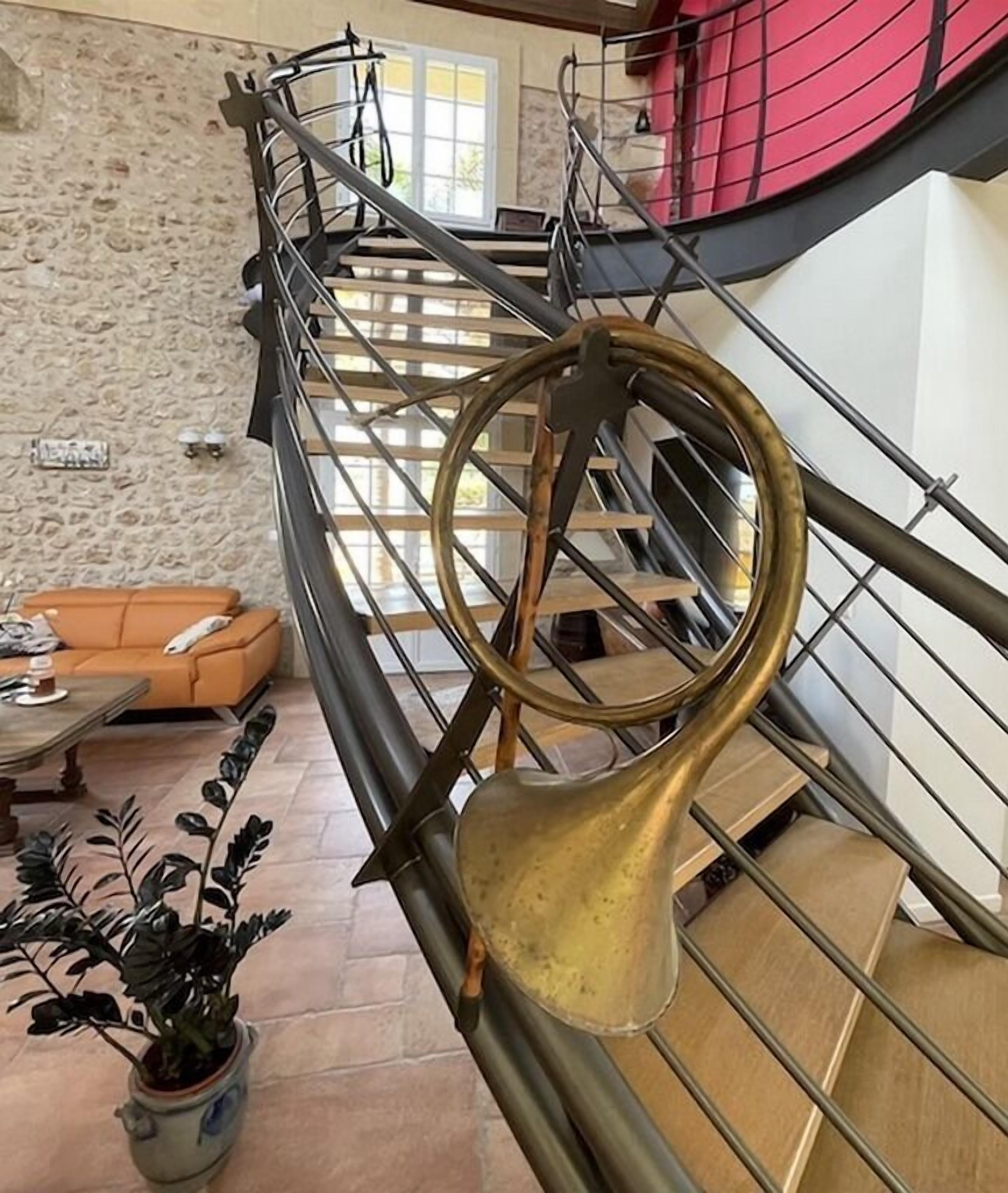 Una escalera con barandilla de latón y una maceta al pie.