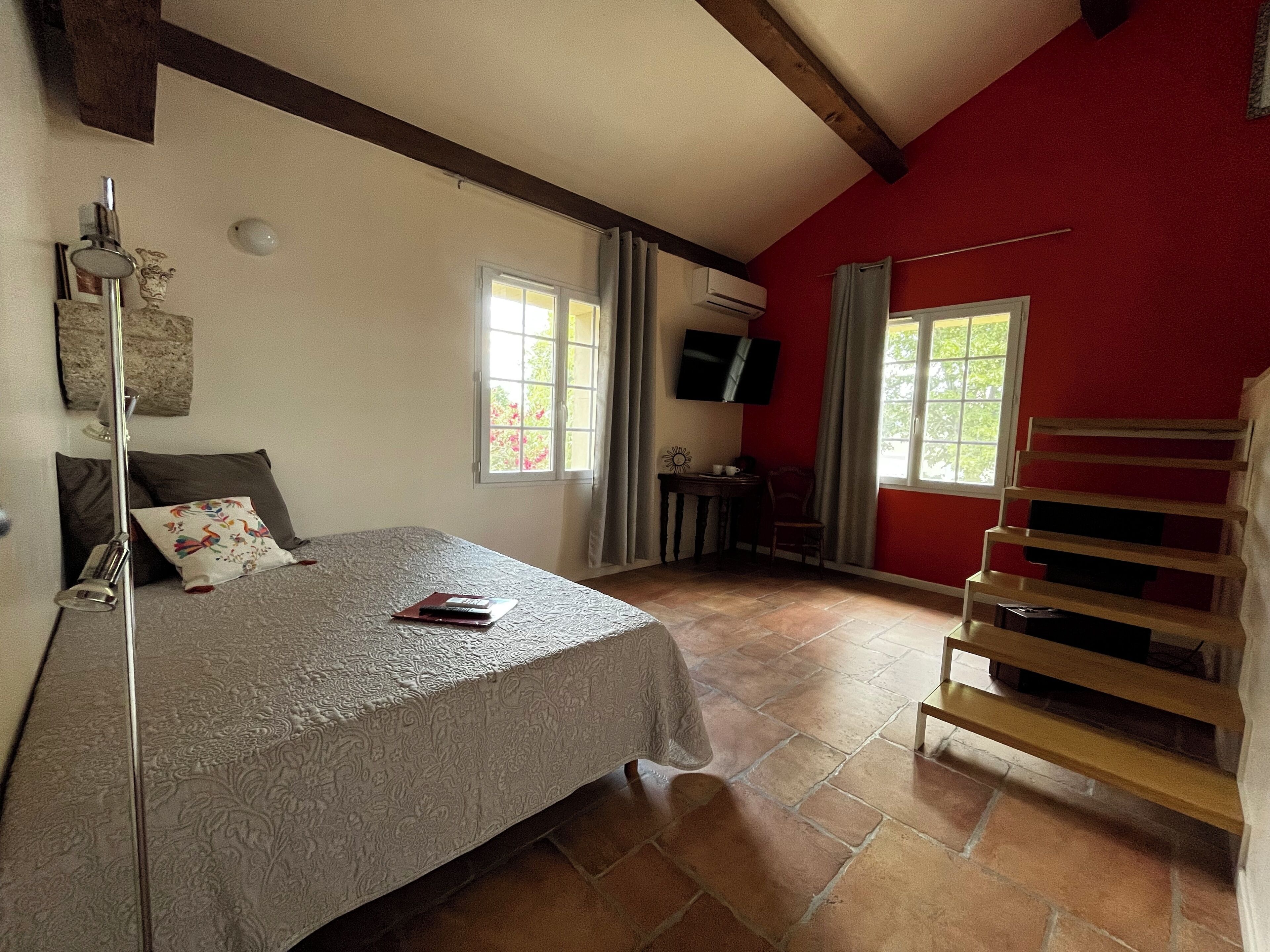 A bedroom with a bed, a bedside table, a TV, and a window.