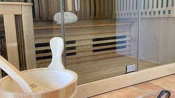 A sauna room with a wooden bench, a wooden bucket, and a sauna brush.