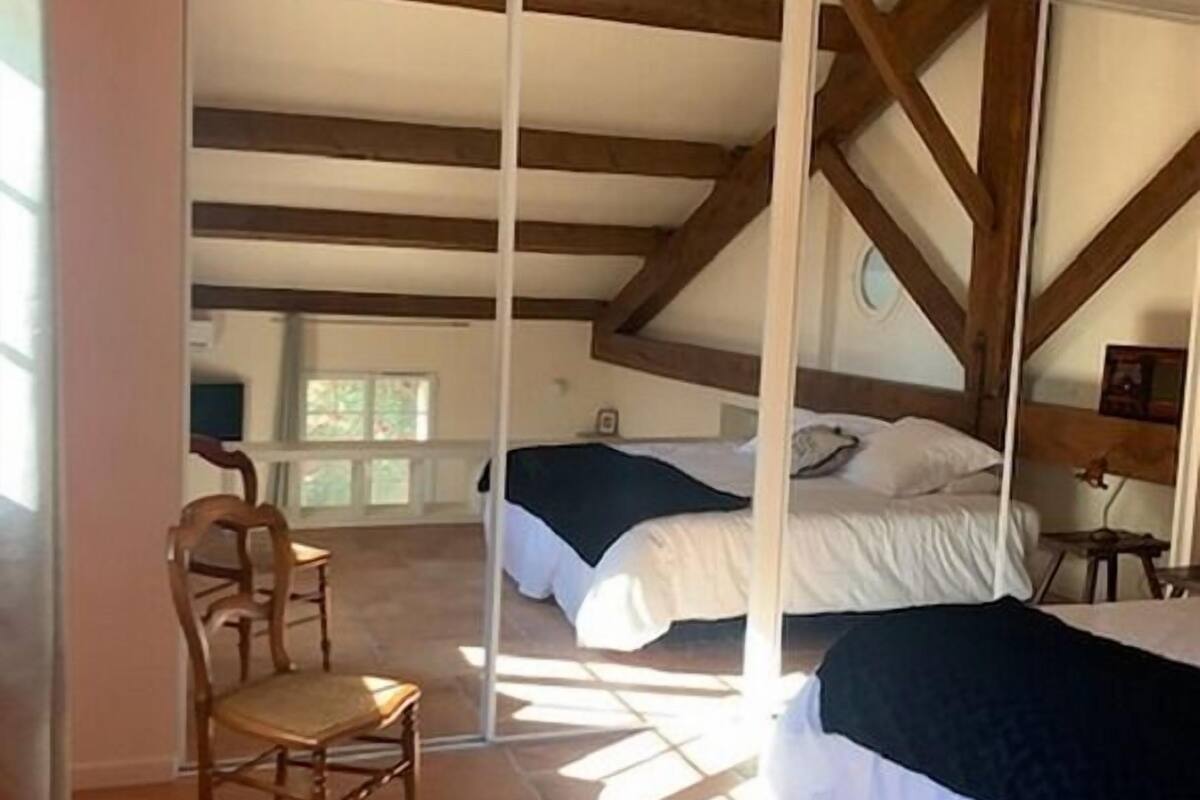 A bedroom with a bed, a chair, and a window.